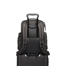 Load image into Gallery viewer, Back panel view showing the telescopic handle of a suitcase passing through the backpack&#39;s back strap to hold it in place. 
