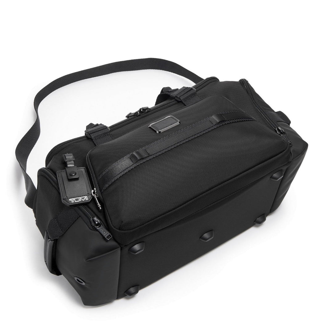 The black duffel laid on its back panel, showing the five short stub legs at the bottom panel to keep the bag clean.