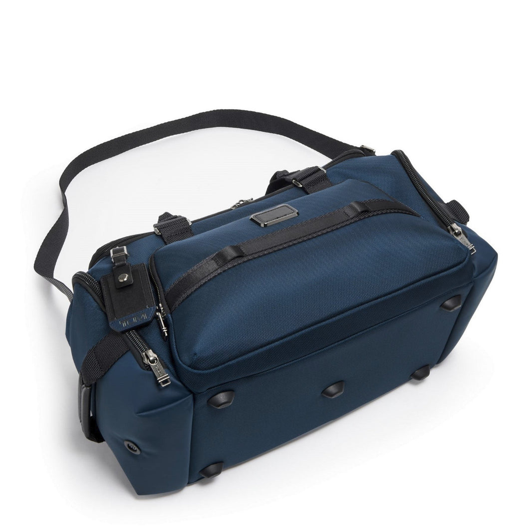 The navy blue duffel laid on its back panel, showing the five short stub legs at the bottom panel to keep the bag clean.