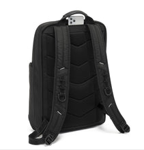 Load image into Gallery viewer, Angled back panel view of the backpack with a cellphone peeking from the pocket underneath the top grab handle. 

